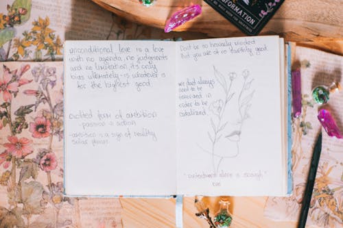 Free A notebook with a pen and flowers on it Stock Photo