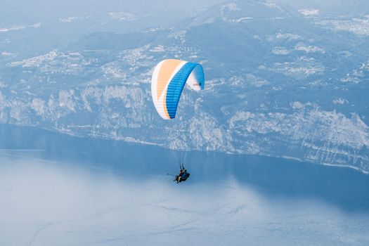 Paraglider soaring above a stunning lake with mountainous backdrop, capturing adventure from above.