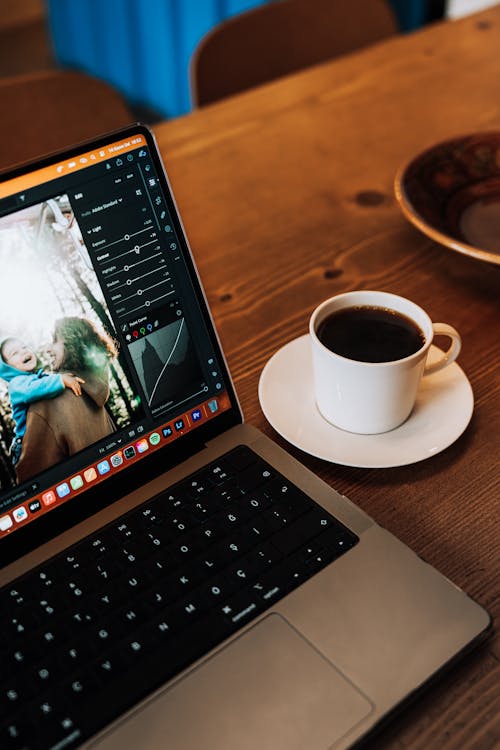 Laptop and a Cup of Coffee Standing on the Table 