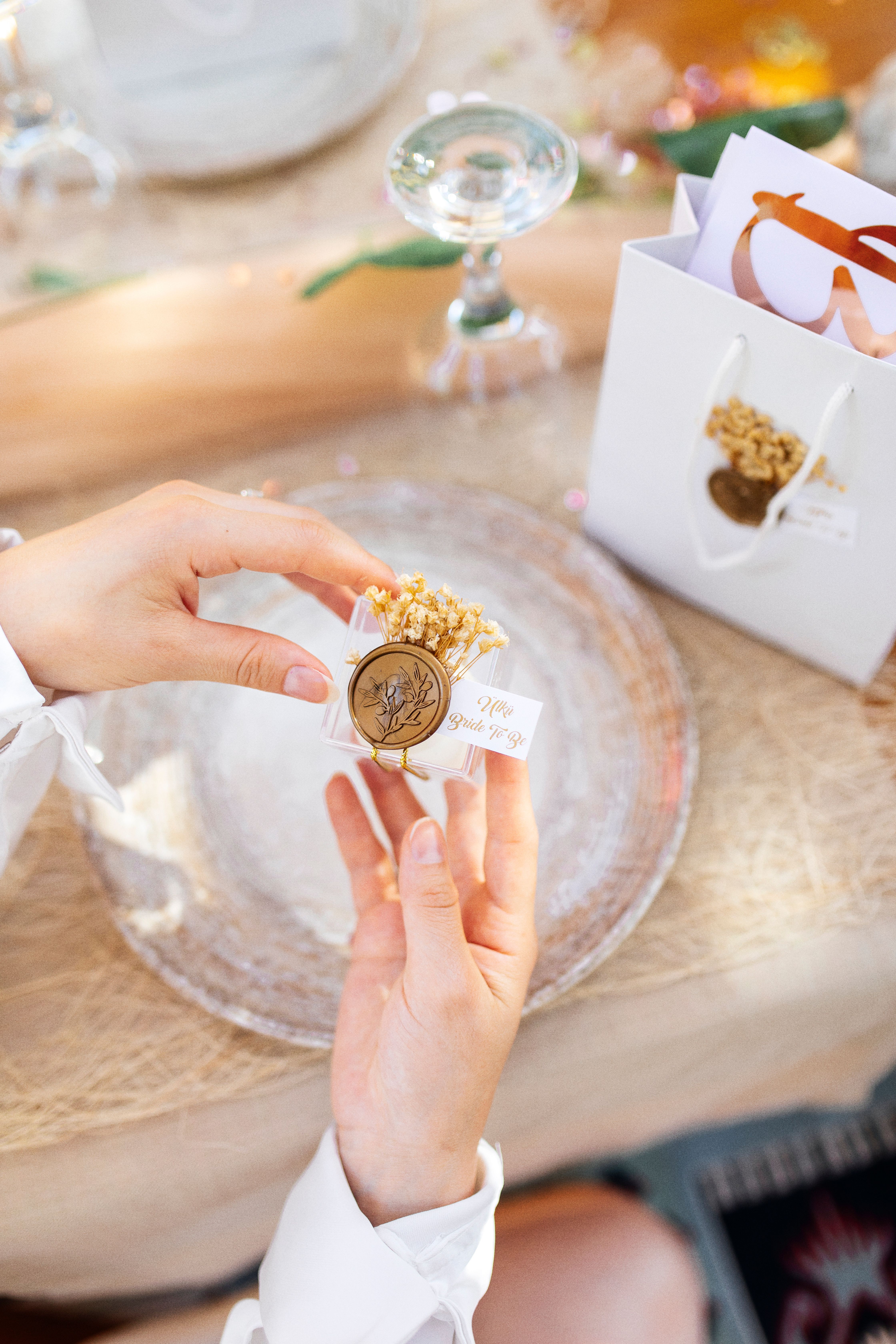 Close-up of woman holding a gift with a wax seal, set on a beautifully decorated table.