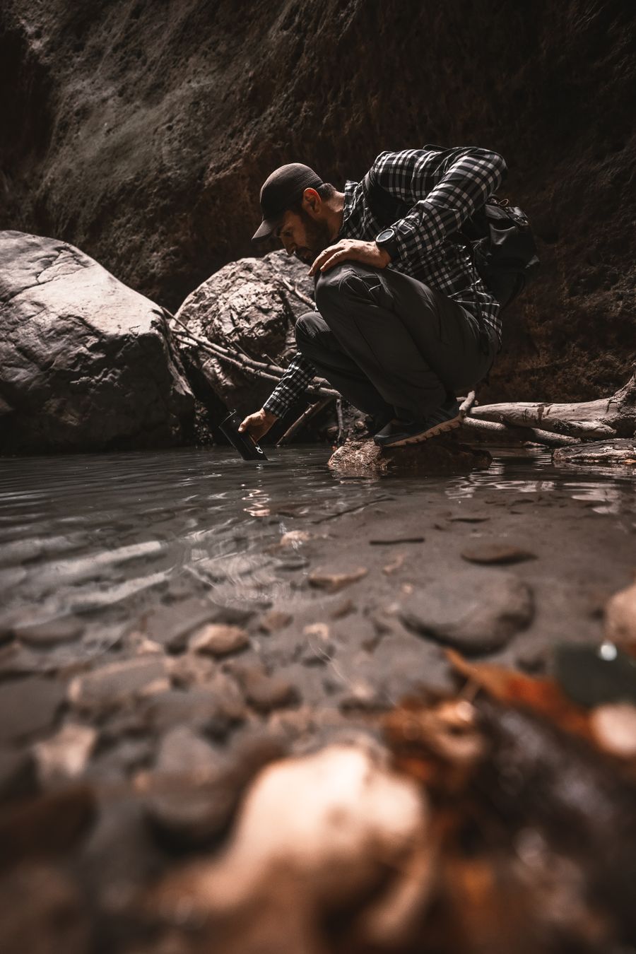 Man filtering water from a stream in the mountains