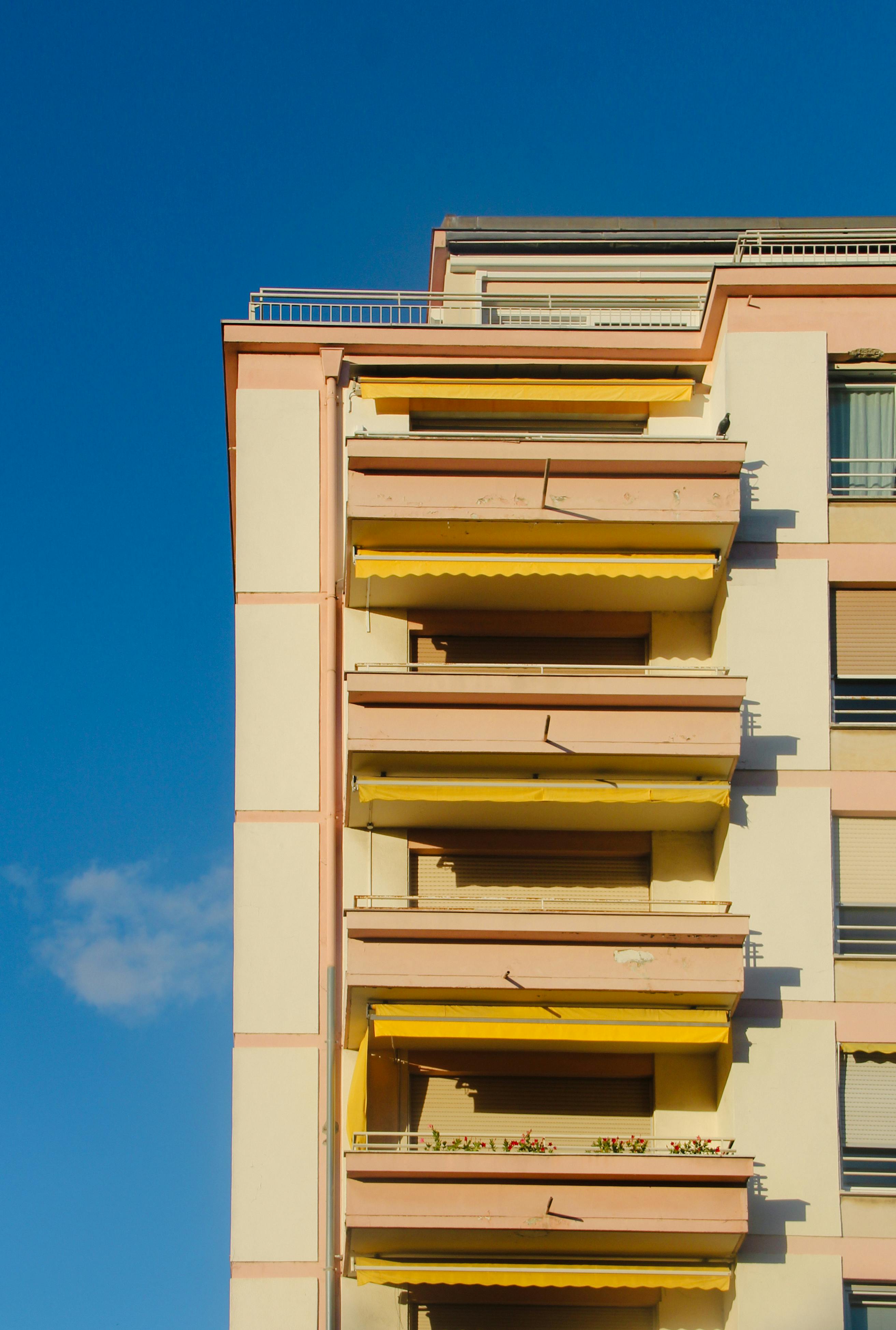Vibrant apartment building in Strasbourg, France featuring pink and yellow accents against a clear blue sky.