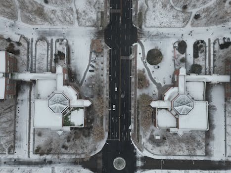 Top-down aerial view capturing the symmetrical city streets and architecture blanketed in snow during winter.