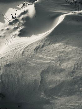 Aerial view showcasing a textured snowy landscape during winter with two distant figures.