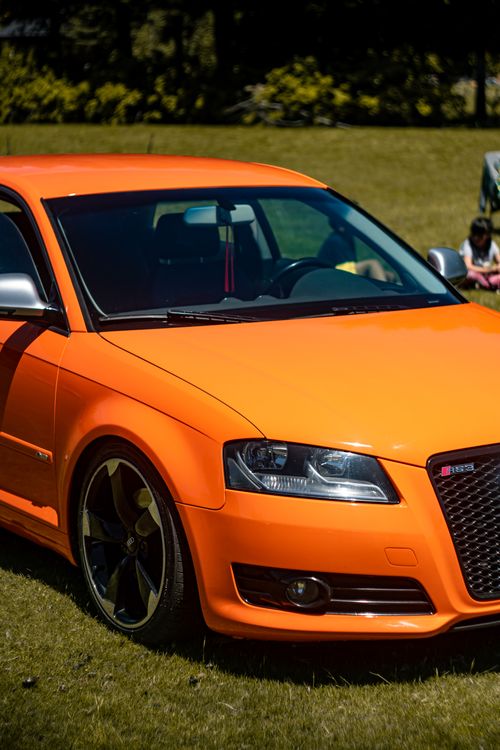 Free A striking orange sports car parked on a sunny day in El Bolsón, Argentina. Stock Photo