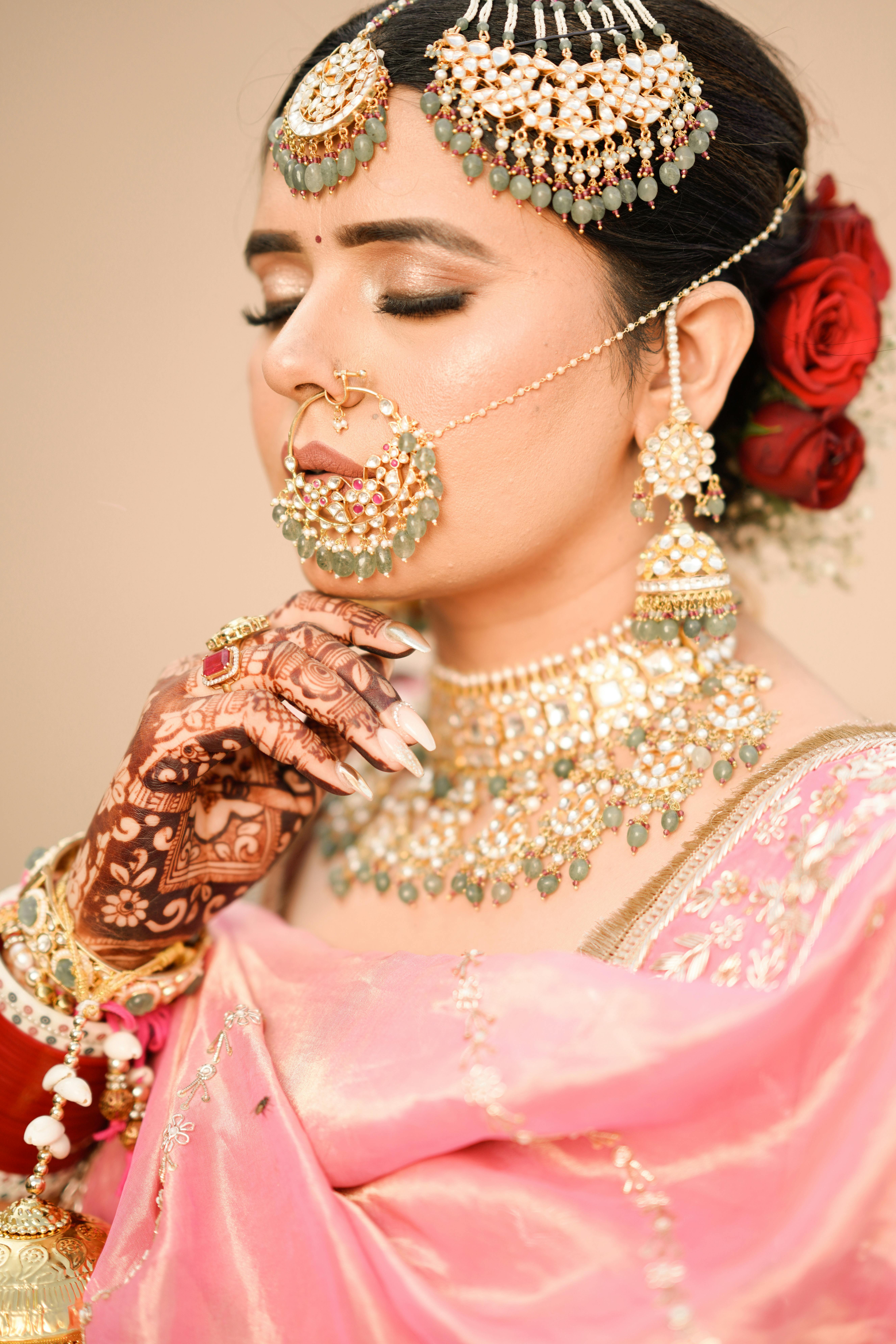 A beautiful Indian bride in traditional pink sari with intricate jewelry and henna tattoos.