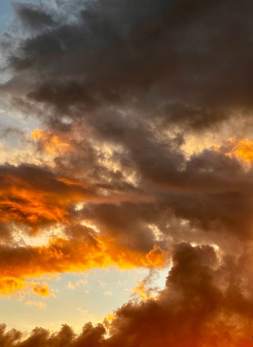 Free Vivid orange and dark clouds during a dramatic sunset, creating a striking sky scene. Stock Photo
