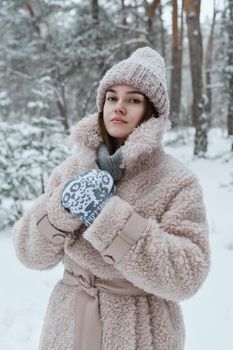 Stylish woman in faux fur coat posing confidently in a snowy forest landscape.