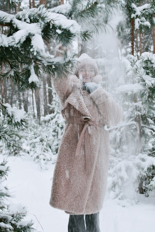 Woman in Faux Fur Knocking Snow Off a Branch on Herself