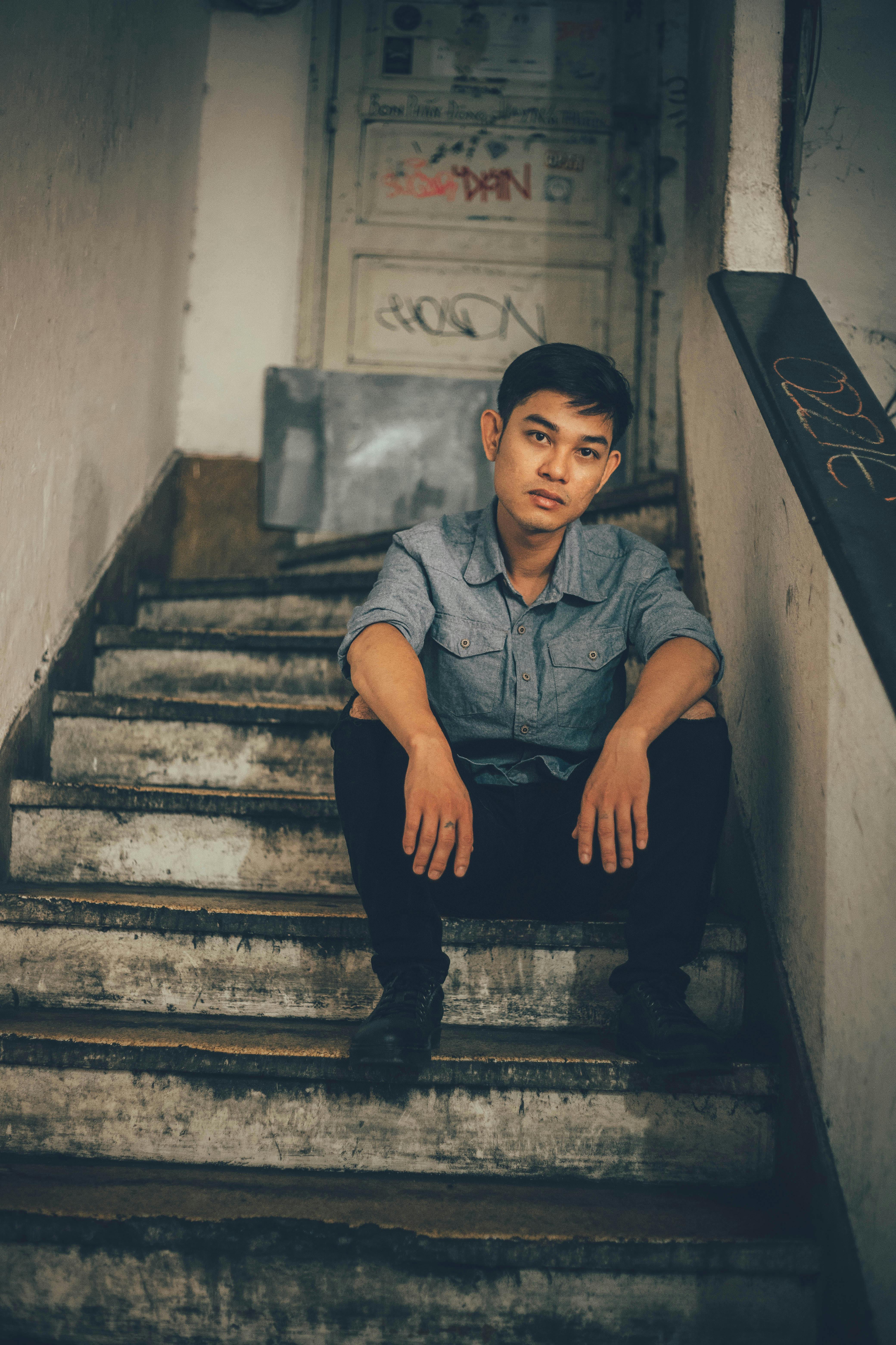 無料 物思いにふける若い男が、落書きに囲まれた都会の階段に座り、陰鬱な雰囲気を醸し出している。 写真素材