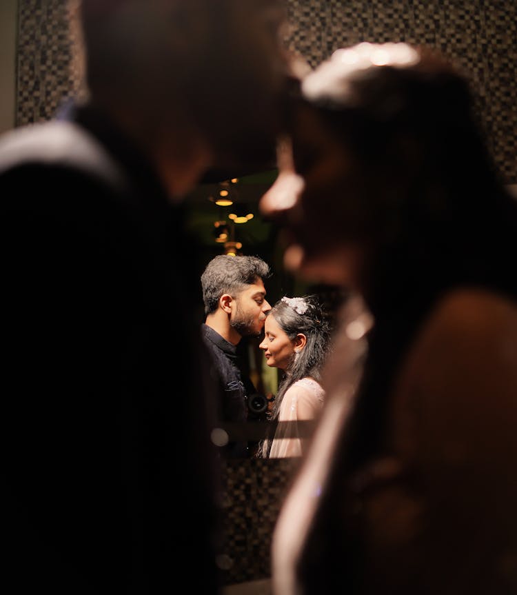 Mirror Reflection Of Man Kissing Woman On The Forehead