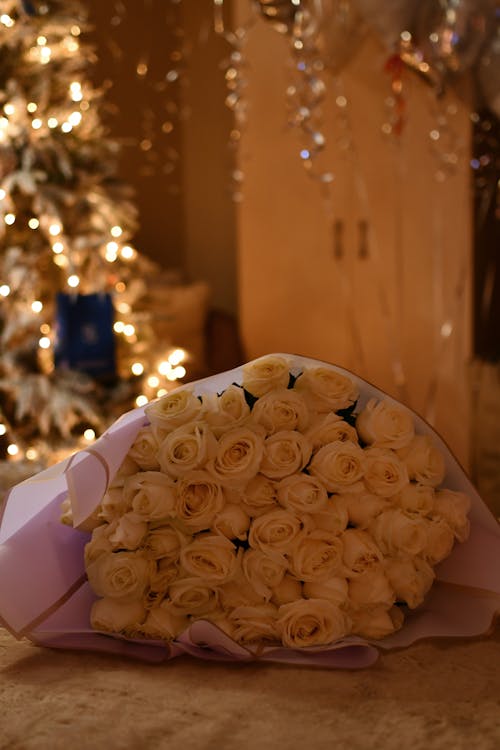 A Bouquet of Roses Lying on the Background of a Christmas Tree