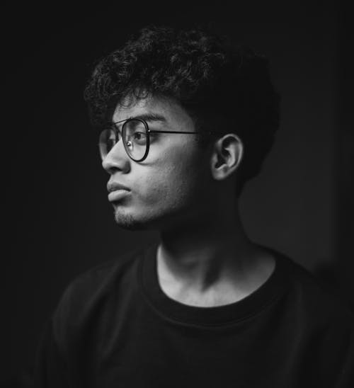 Black and White Photo of a Young Man in Eyeglasses Looking Away