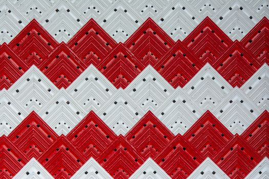Decorative red and white zigzag pattern with geometric tiles creating a bold visual design.