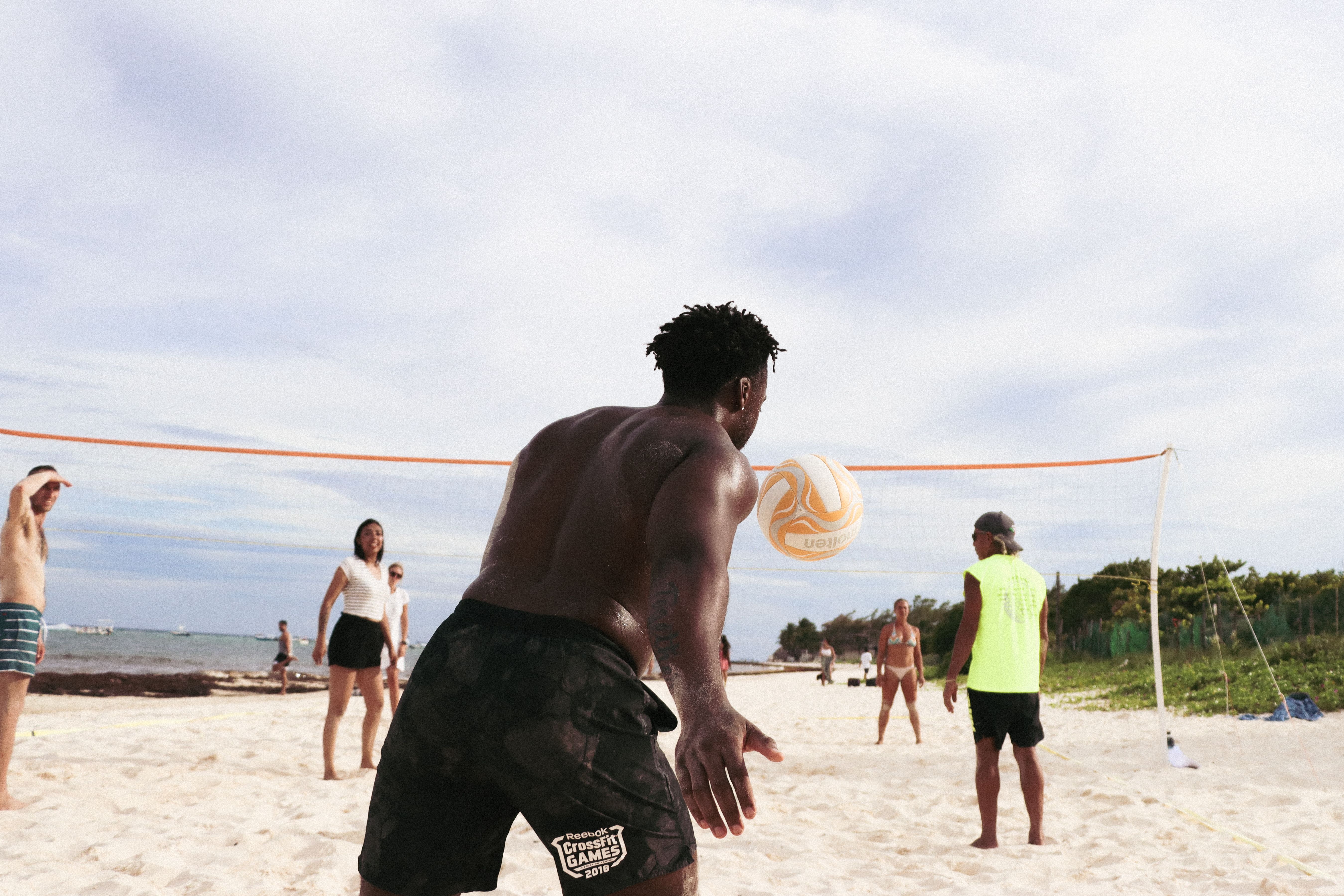 A group of adults playing beach volleyball on a sunny day.