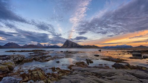 Free Breathtaking sunset over rugged coastal landscape in Norway with snow-capped mountains. Stock Photo