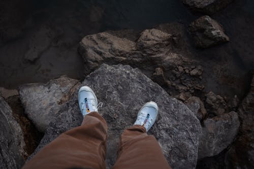 Man in Sneakers Standing on Rock