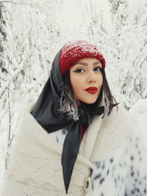 Young Woman in Winter Clothing Standing in a Snowy Forest 