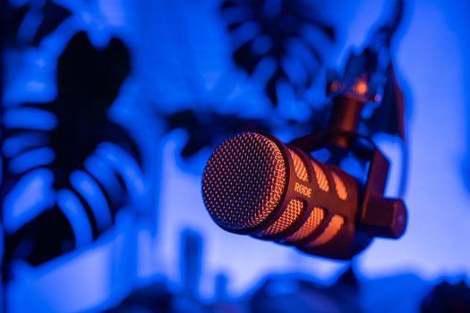 Dynamic close-up of a RØDE microphone with blue lighting, ideal for podcast themes.