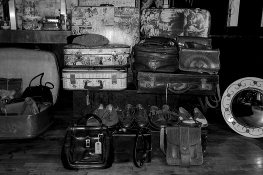 Black and white display of vintage suitcases, bags, and shoes.