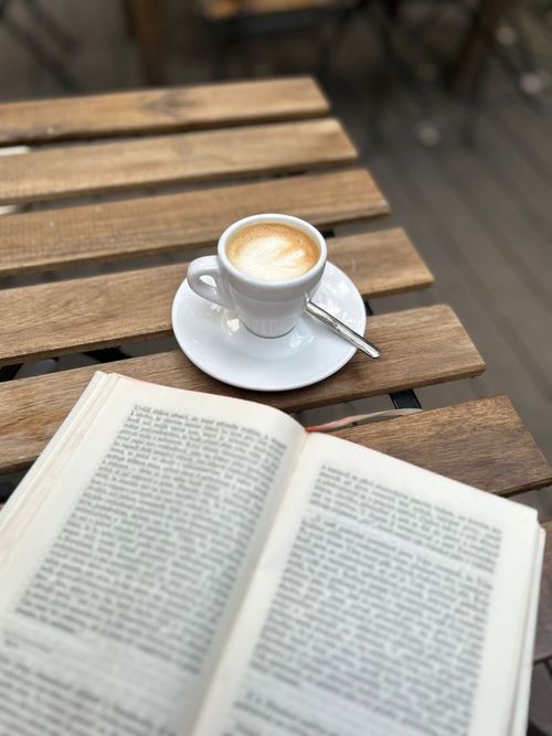 Free A serene setup with a coffee cup and book, perfect for relaxation at a café in Prague. Stock Photo