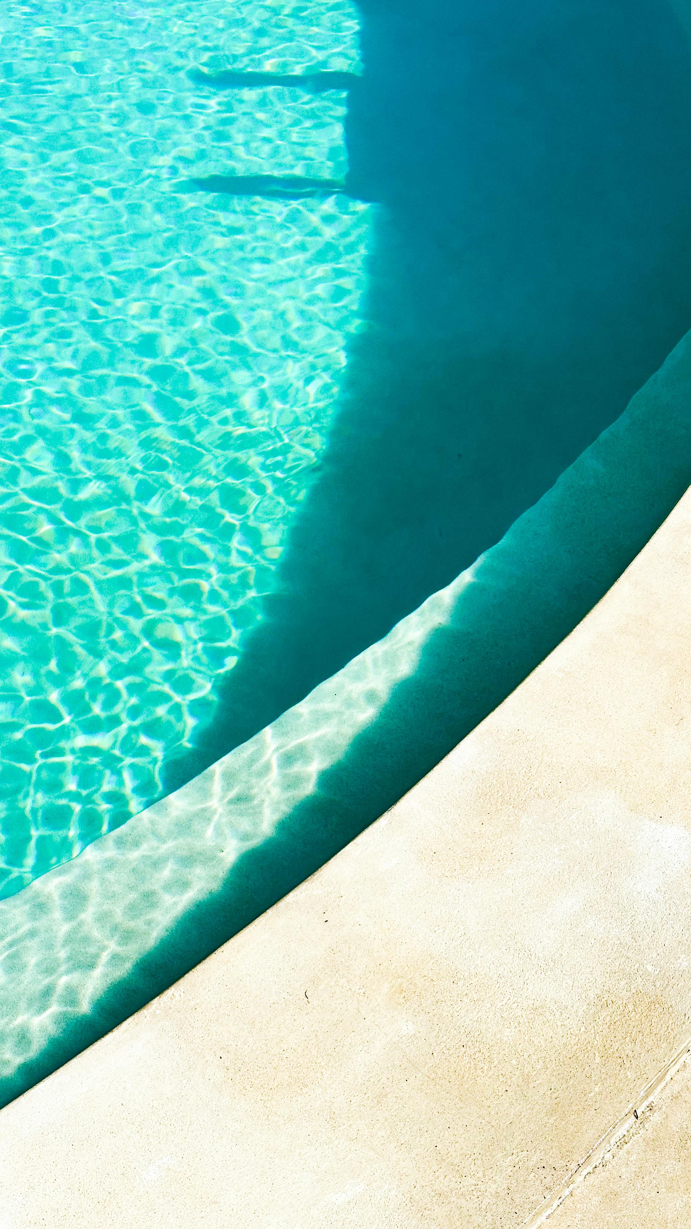 Free Bright and refreshing view of a sunlit pool with vibrant blue water, perfect for summer vibes. Stock Photo