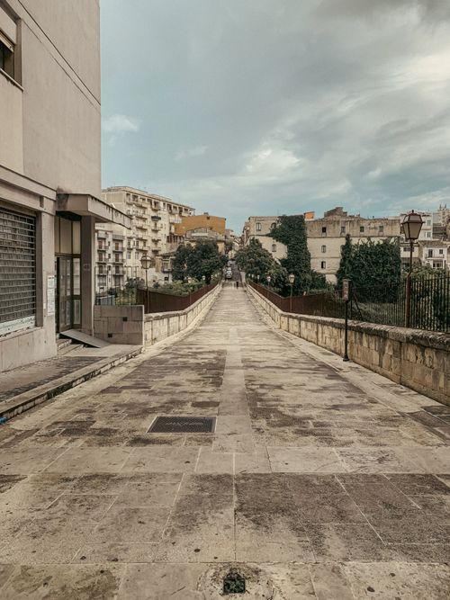 Free A peaceful footbridge in Ragusa, Sicily, showcasing urban architecture and residential buildings. Stock Photo