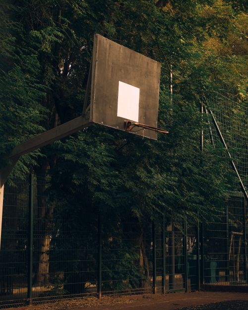 Free Basketball hoop on an outdoor court in Sétif, Algeria, with surrounding trees. Stock Photo