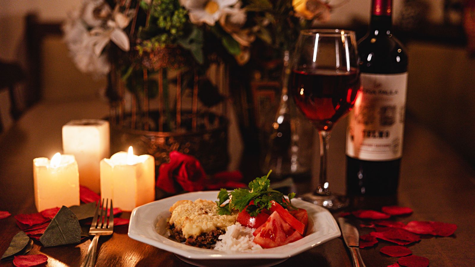 Romantic candlelit dinner table set with wine