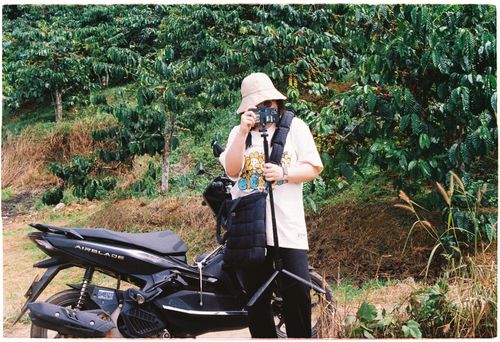Free A woman with a camera on a tripod beside a motor scooter in a rural setting. Stock Photo