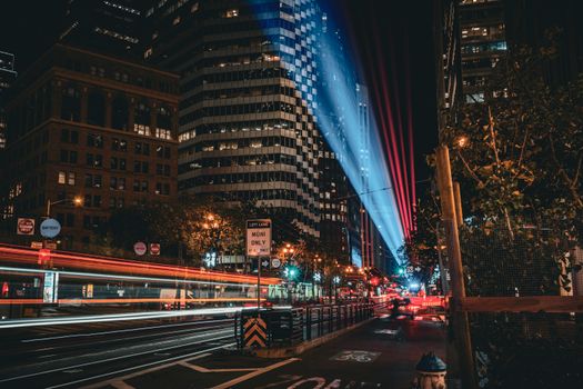 Dynamic cityscape at night featuring modern architecture and vibrant light trails.