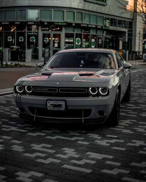 Free A sleek gray sports car parked in a modern cityscape during twilight, showcasing elegance and style. Stock Photo