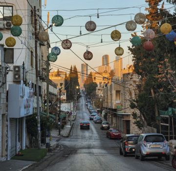 Street scene with hanging decorations and distant skyline at sunset.