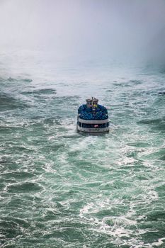 Scenic view of a tourist boat braving the misty waters of Niagara Falls.