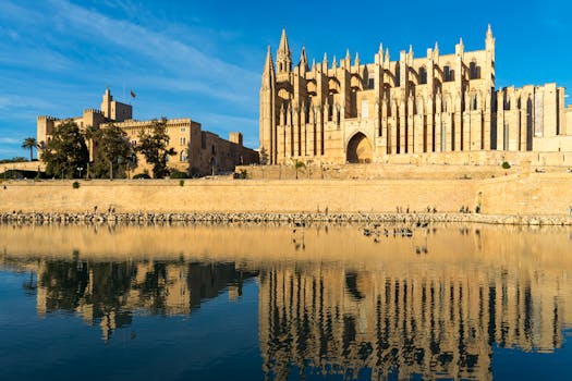 Stunning view of the Gothic Palma Cathedral reflecting in the water under a clear blue sky.