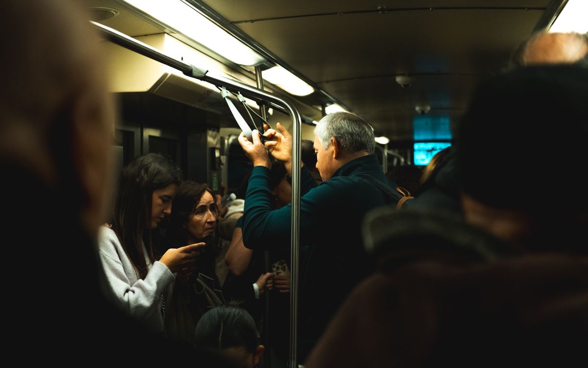 Passengers commuting in a crowded subway train, illuminated by overhead lights.