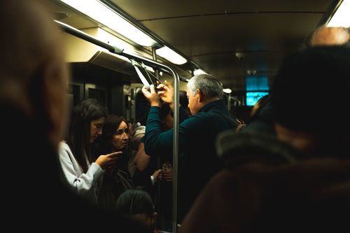Free Passengers commuting in a crowded subway train, illuminated by overhead lights. Stock Photo