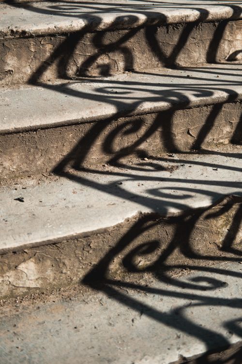 Free Shadows of ornate ironwork create artistic patterns on old concrete steps. Stock Photo