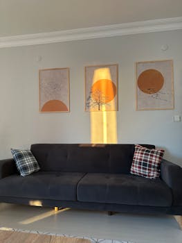 A chic minimalist living room featuring framed posters and a stylish dark sofa.