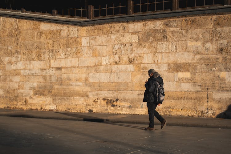 Person Walking Against Stone Wall