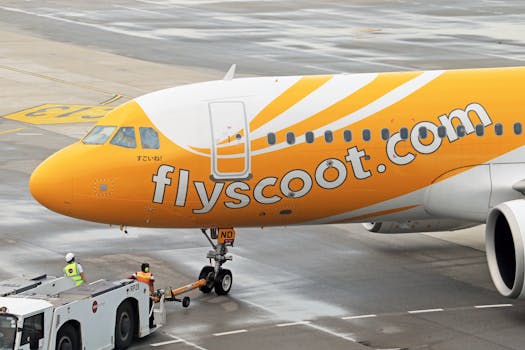 Scoot Airbus A320 being towed by a pushback tug at an airport apron.