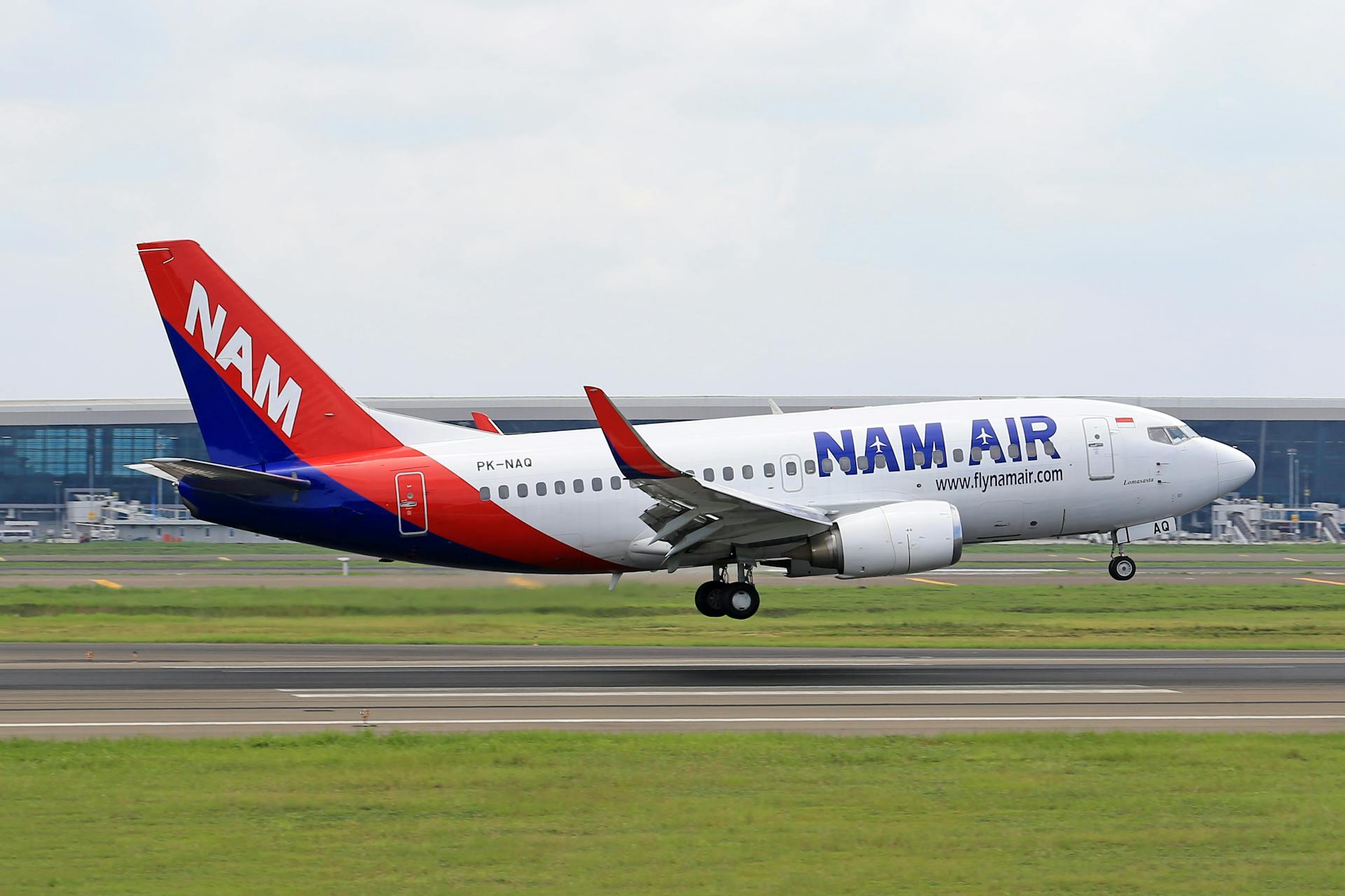 NAM Air Boeing 737 airplane taking off from a runway, captured during daytime.