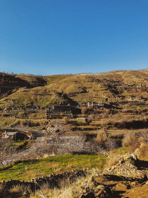Free Explore an abandoned village nestled in a dry, rolling hillside landscape under a clear blue sky. Stock Photo
