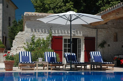Striped Loungers under Umbrella by Swimming Pool