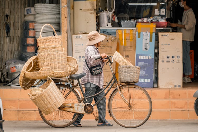 Woman Leading Bike With Wicker Basket On