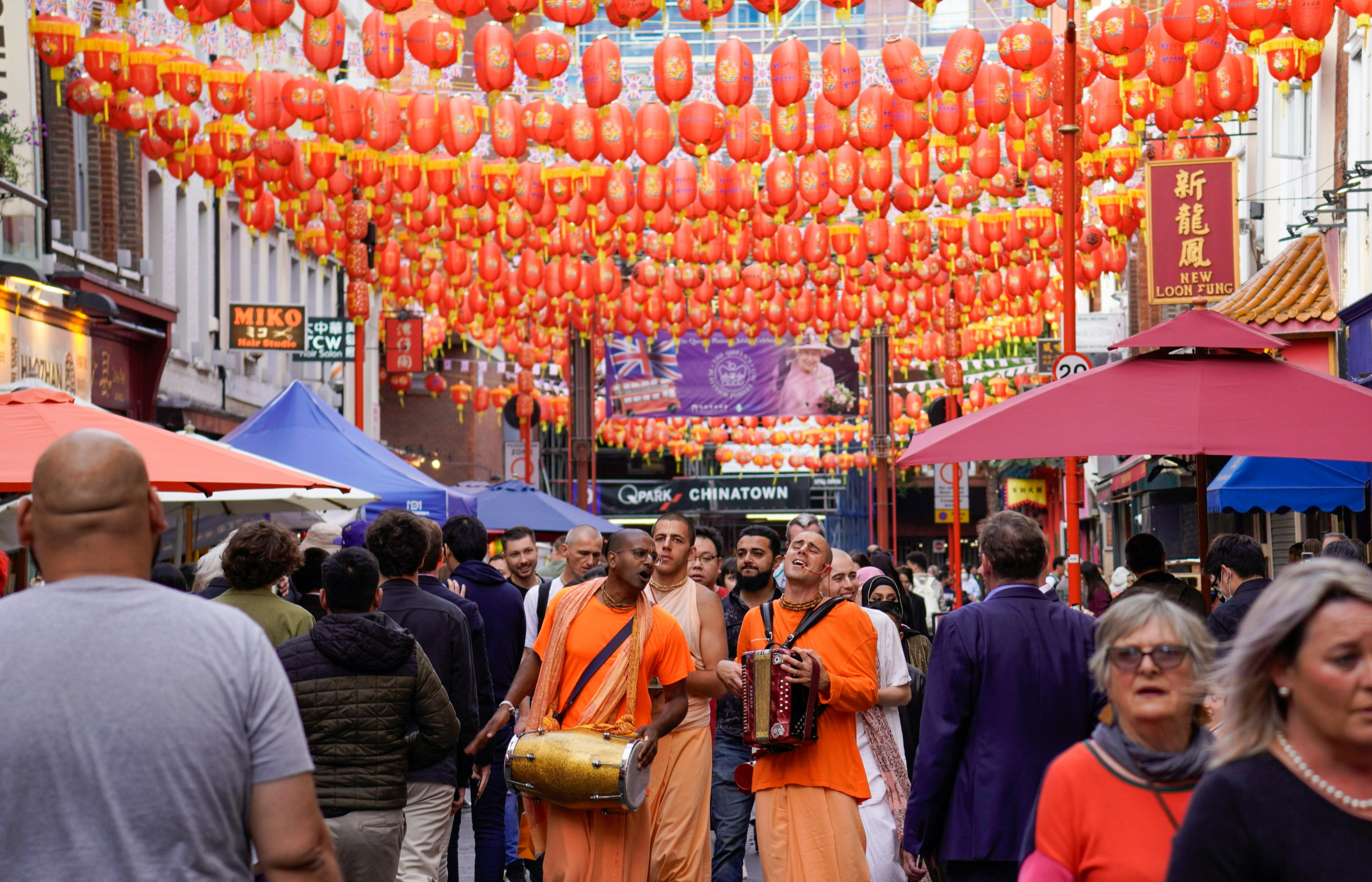 Musicians and crowds celebrate under lanterns in London's iconic Chinatown.
