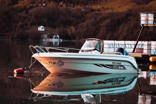 A tranquil and picturesque scene of a motorboat moored on a calm lake with scenic reflections. — photo by Nemanja Ciric