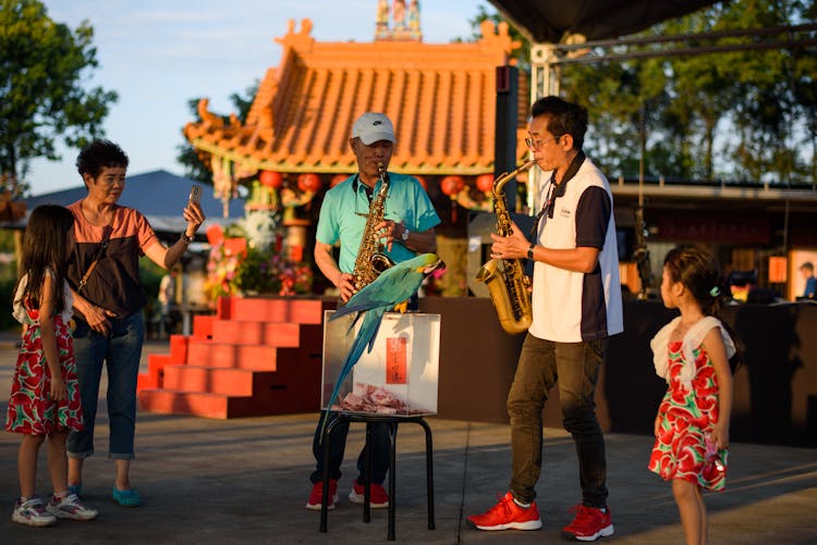 Woman And Children Watching Men Playing Saxophone