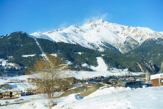Scenic view of a snowy village nestled by mountains showcasing winter beauty.