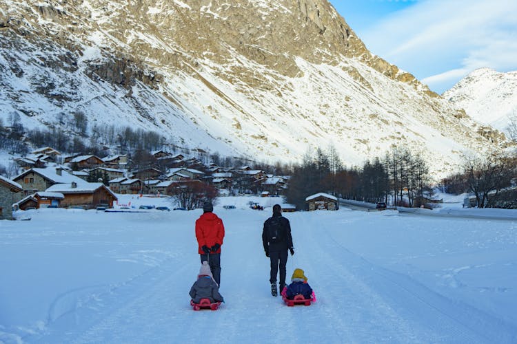 Parents Towing Children On Sleighs In Village